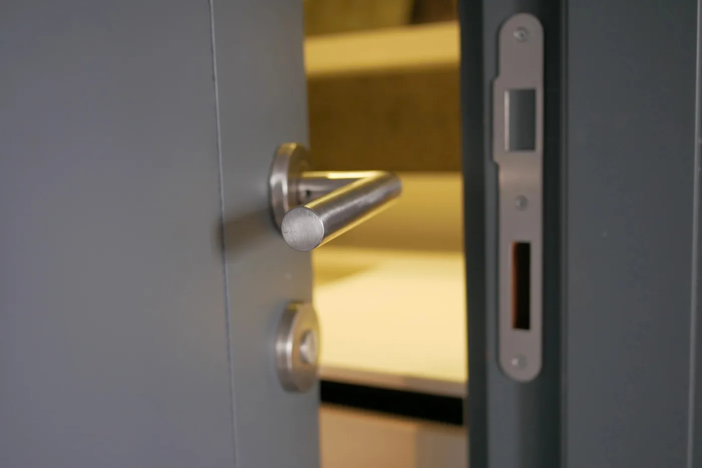 Serrure encastrée et gâche laiton sur une porte d'immeuble francilien